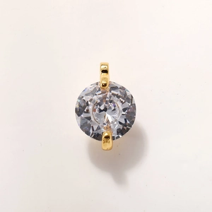Macro detail of round cut clear zircon pendant with gold plated double claw setting