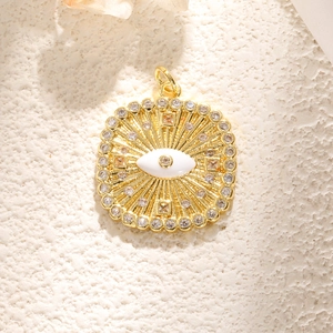 Makroaufnahme von Gold-Anhänger mit blauem Auge, Zirkonia-Besatz und Reliefmuster