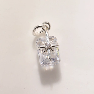 Close-up of rectangular crystal pendant with silver starburst and shiny metal loop