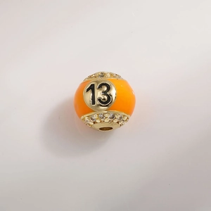 Detailed macro shot of 12mm orange enamel charm bead with gold number 13 and zircons