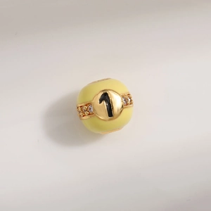 Detailed macro view of yellow enamel charm bead with sparkling number 1 and crystals