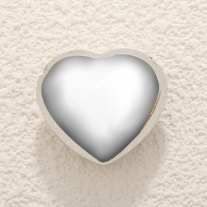 Minimalist silver heart pendant with polished mirror finish on textured background