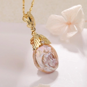 Macro shot of baroque pearl necklace with golden maple leaf pendant and shiny beads