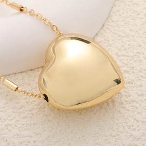 Close-up of a 3D heart-shaped gold plated pendant with a polished mirror finish surface