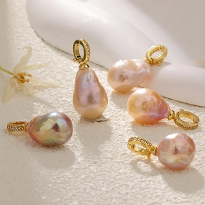 Cinq pendentifs perles d'eau douce baroques avec fermoirs en zircon doré sur fond blanc