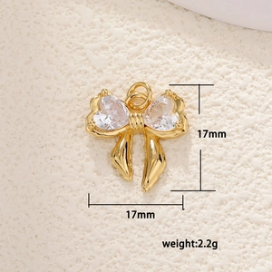 Macro detail of a 17mm gold bow pendant with heart-shaped cubic zirconia and ring
