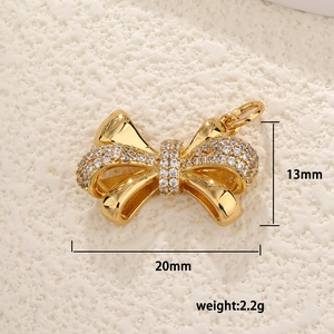 Macro detail of a 20mm gold bow pendant with sparkling zircons and dimensions marked