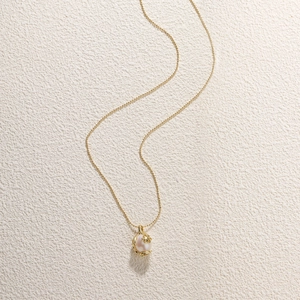 Detailed shot of baroque pearl pendant with golden flower on a beaded chain