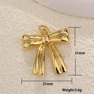 Macro view of gold bow pendant with dimensions and weight specs on a textured surface