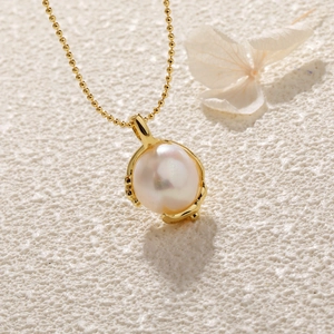 Close-up of a lustrous baroque pearl pendant on a delicate gold bead chain with a flower
