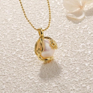 Close-up of a white baroque pearl pendant encased in a golden filigree floral frame