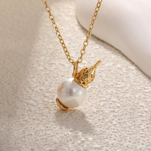 Detail of baroque pearl necklace featuring golden rose floral cap on a stone surface