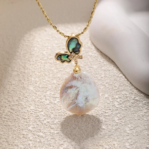 Macro view of butterfly pendant with green shell, diamond accents, and baroque pearl