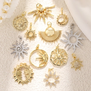 Detail of 18K gold and silver celestial charms with sun and moon designs on white fabric