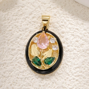Detail of vintage oval pendant with pink stone, green leaves and gold plating