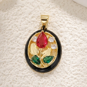 Detailed macro of oval floral pendant with red and green gems and black enamel finish