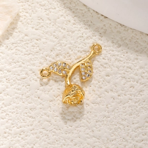 Macro shot of gold-plated rose charm with cubic zirconia leaves for jewelry making