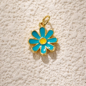 Macro detail of blue daisy flower pendant with gold plating and enamel inlay