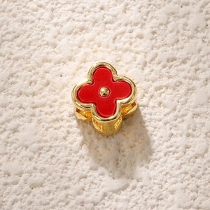 Macro shot of gold-plated four-petal flower bead with red enamel for DIY jewelry