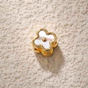 Macro view of gold-plated clover charm with white mother-of-pearl inlay and hollow design