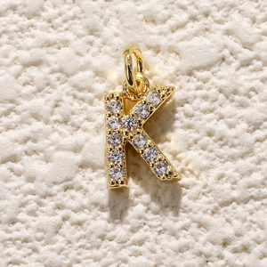 Macro-opname van vergulde letter K hanger met zirkonia voor DIY-sieraden maken