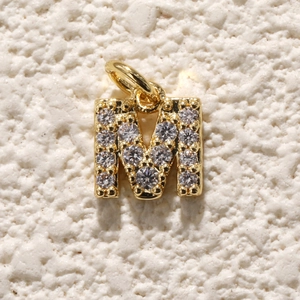 Macro-opname van vergulde letter M hanger met zirkonia voor DIY-sieraden maken