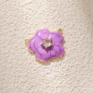 Macro detail of purple enamel flower charm with central zircon and gold plated finish