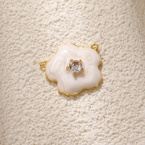 Detail of flower charm with white enamel petals, gold plating and crystal center