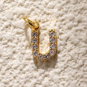 Detail van vergulde letter U hanger met fonkelende zirkonia inleg voor doe-het-zelf