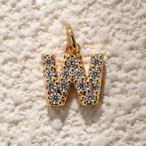 Macro-opname van vergulde letter W hanger met micro-gepaviseerde zirkonia steentjes