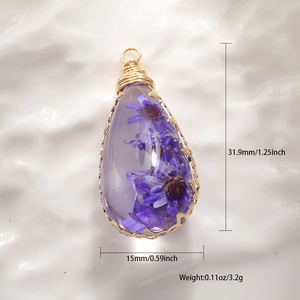 Macro view of handmade drop pendant with purple dried flowers and gold wire wrap