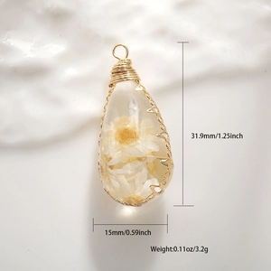 Macro detail of drop resin pendant with white dried flowers and gold wire wrap