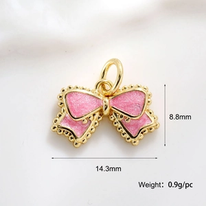 Detailed view of pink enamel bow pendant with gold plating and dimensions 14.3mm by 8.8mm