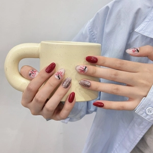 Handmade oval press-on nails featuring red plum blossom patterns and gold glitter accents