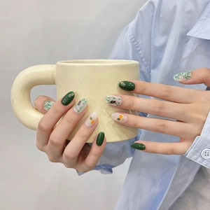 Faux ongles faits main avec vernis vert foncé et motifs de bambou et panda sur pointes ovales