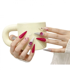 Pink and silver stiletto press-on nails with K9 crystals holding a beige ceramic cup