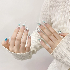 Unghie lunghe a stiletto con cristalli blu a cuore e glitter argentati per un look elegante