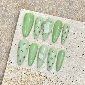 Handmade light green almond press-on nails with cat eye finish and gemstone accents