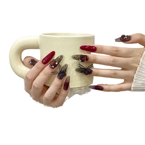 Handmade press-on nails with red lace, black bows, and rhinestones in almond shape
