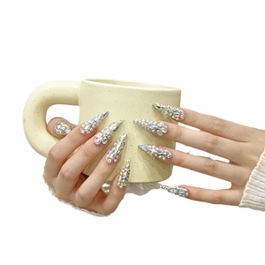 Luxurious long almond press-on nails with full aurora crystals on a model holding a cup