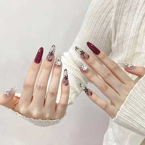 Handmade cherry red almond press-on nails with hand-painted florals and luxury crystal gems