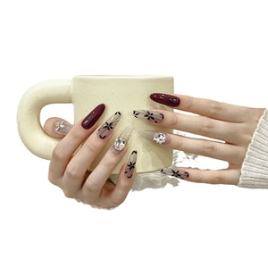 Handmade cherry red press-on nails with almond shape, floral patterns and 3D bow charms
