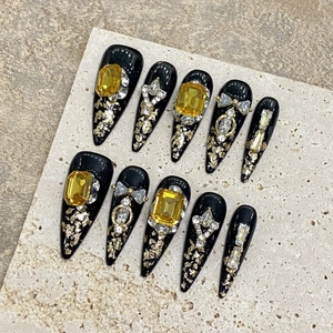 Luxurious handmade press-on nails with black base, amber rhinestones, and gold charms