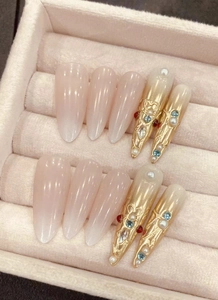 Close-up of handmade palace style press-on nails with blue rhinestones and pearls