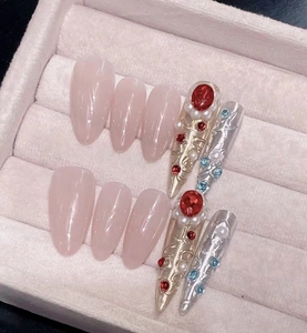 Macro shot of luxury press-on nails with vintage crystals and pearls in a velvet jewelry box