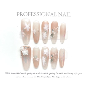 Détail de faux ongles en amande avec papillons 3D et décorations florales pailletées