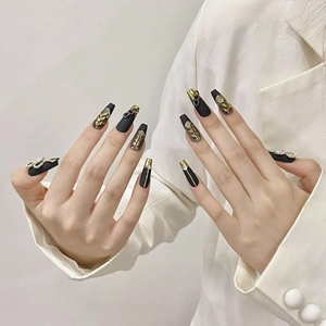 Handmade matte black press-on nails with golden leaf relief and metallic chain charms