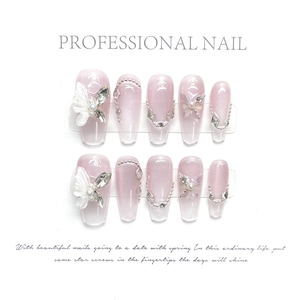 Détail de faux ongles faits main avec papillons 3D, perles et strass brillants