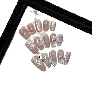 Faux ongles faits main avec motifs de cœur œil de chat rose et paillettes papillon