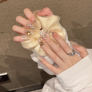Handmade coffin press-on nails with nude pink base, black dots, and silver butterfly charms